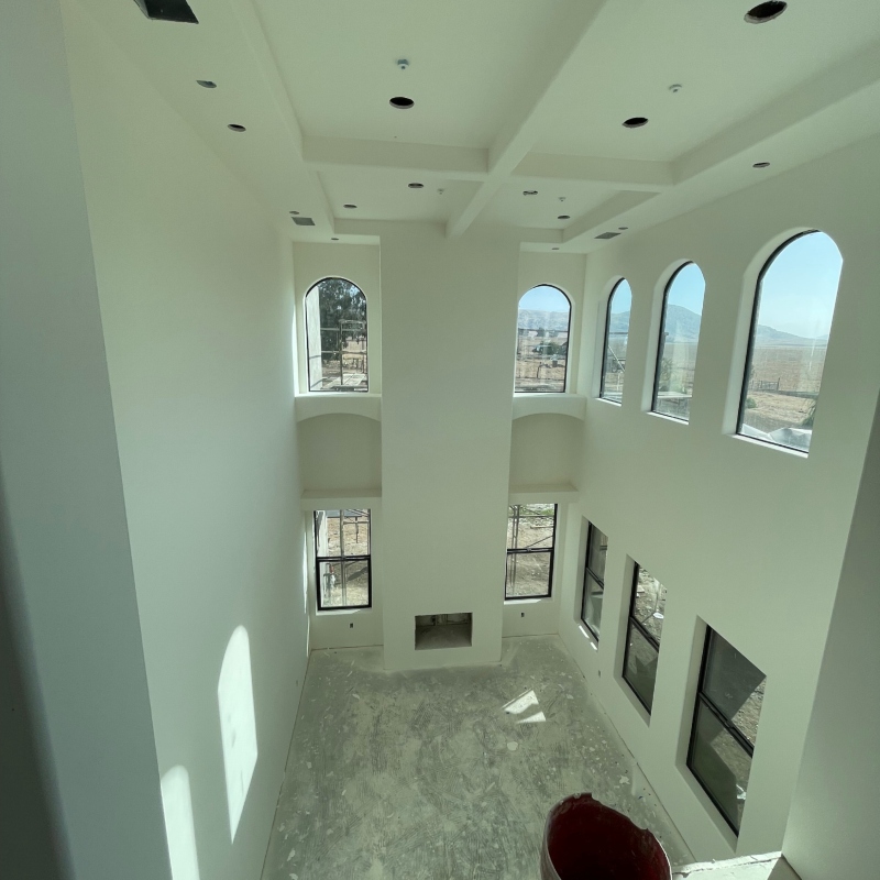Multiple images showcasing the transformation of a space through drywall installation, from unfinished to finished
