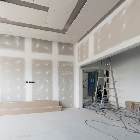 Unfinished interior of a house under construction, showing drywall installation and a ladder
