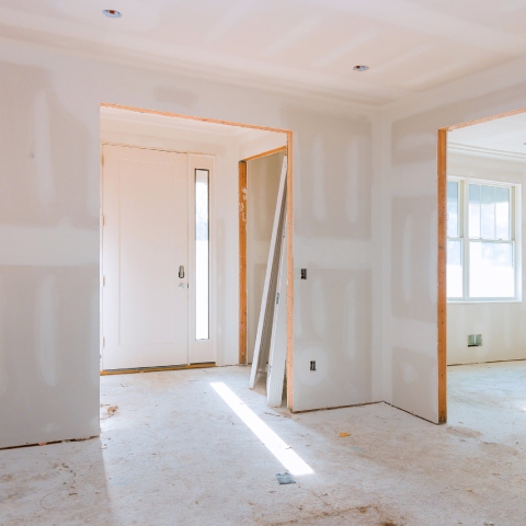Interior of a house under construction, showing unfinished drywall and a partially installed door